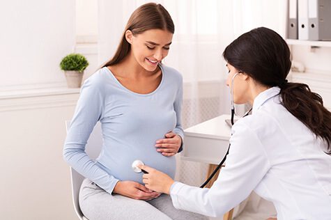 SMWC - doctor examining pregnant woman holding stethoscope near belly
